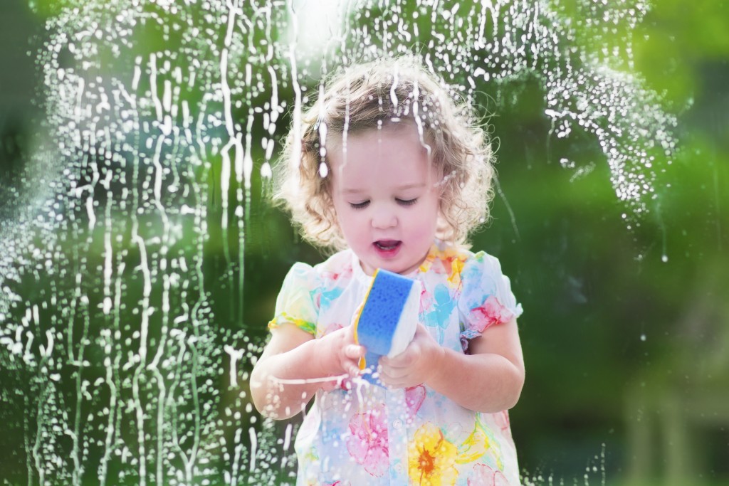 Little girl washing a window